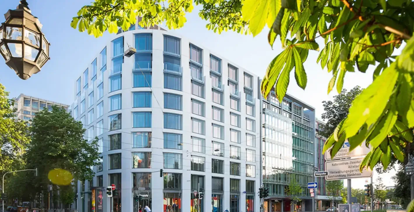 Das helle Eckgebäude an der Königsallee, in dem die Praxis liegt, von der Straße aus gesehen
